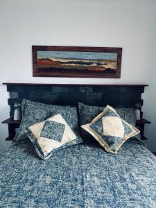 a bed with two pillows and a painting on the wall at Departamento BELGRANO CENTRO in Paraná