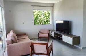 Village Novo Barra do Jacuípe في كامساري: غرفة معيشة مع أريكة وتلفزيون