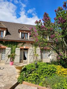 a house with a flowering tree in front of it at Chambres d'Hotes chez Renée in Le Charmel