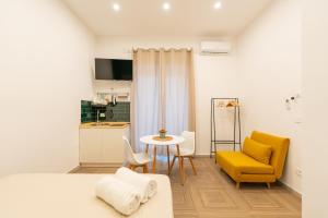 Sala de estar con silla amarilla y mesa en R&D Scassacocchi apartments 15, en Nápoles