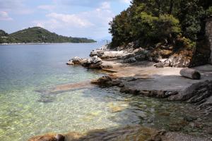 a beach with rocks and the water and trees at Apartments by the sea Sobra, Mljet - 22329 in Babino Polje