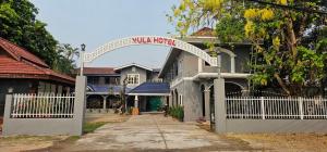 a white fence in front of a house with a gate at Yula Hotel Thatluang in Vientiane