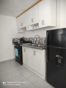 a kitchen with a black refrigerator and white cabinets at tropicana sur apt221 in Sosúa