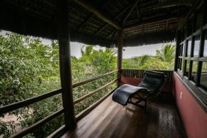 a balcony of a house with a chair and trees at Pousada Colmeia - Praia de Santo André, Bahia in Santo André