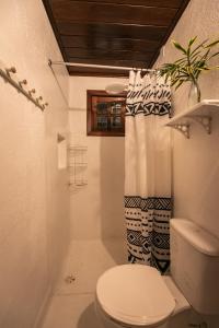 a bathroom with a toilet and a shower curtain at Pousada Colmeia - Praia de Santo André, Bahia in Santo André