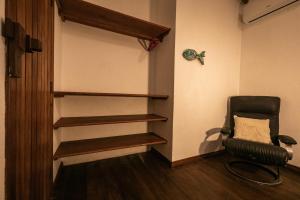 a room with a chair and a shelf in a room at Pousada Colmeia - Praia de Santo André, Bahia in Santo André