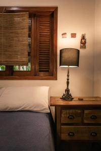 a bedroom with a bed and a table with a lamp at Pousada Colmeia - Praia de Santo André, Bahia in Santo André