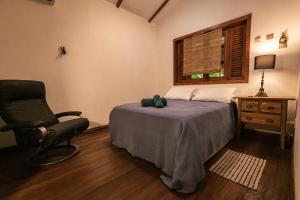 a bedroom with a bed and a chair and a window at Pousada Colmeia - Praia de Santo André, Bahia in Santo André