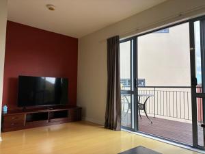 uma sala de estar com uma televisão de ecrã plano e uma varanda em New Lynn Tidy House em Auckland