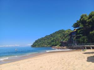 uma praia com uma casa numa colina junto ao oceano em Angra TOP1 Praia Piscina Marina 2 quartos em Angra dos Reis