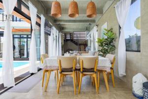 ein Esszimmer mit einem Tisch, Stühlen und einem Pool in der Unterkunft ISLA VILLA 2 Luxury Pool Villa near beach with karaoke video games barbecue in Maribago