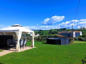 einen Tisch und Stühle unter einem weißen Regenschirm auf einem Rasen in der Unterkunft Casina di Andrea with above ground pool, Capannori in Capannori