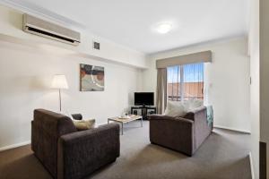 a living room with two chairs and a television at Urban Apt in the Heart of Northbridge in Perth