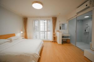 a bedroom with a white bed and a shower at Leye Inn in Yangshuo