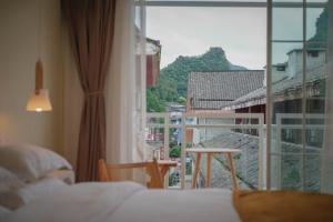 a bedroom with a bed and a view of a balcony at Leye Inn in Yangshuo