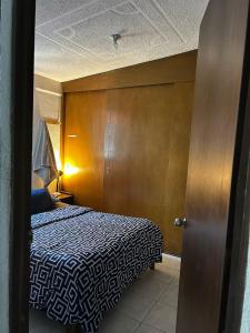 ein Schlafzimmer mit einem Bett und einer Holzwand in der Unterkunft Habitación Cuitláhuac en Apartamento Compartido in Mexiko-Stadt