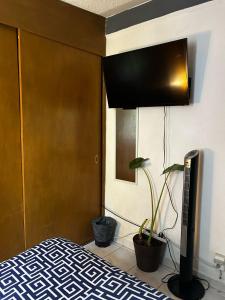 ein Schlafzimmer mit einem Bett, einem TV und einer Anlage in der Unterkunft Habitación Cuitláhuac en Apartamento Compartido in Mexiko-Stadt