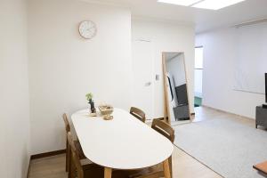 a white dining room with a white table and chairs at Ogeum stay in Seoul