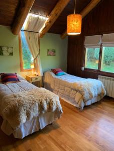 2 łóżka w pokoju z drewnianymi podłogami i oknami w obiekcie Habitación privada en Casa Indra w mieście San Martín de los Andes