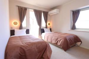a bedroom with two beds and a window at Pension Angelica in Minami Aso