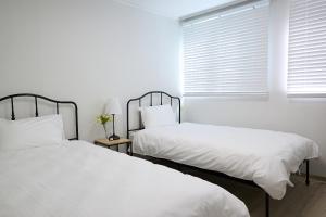 two beds in a white room with a window at Ogeum stay in Seoul
