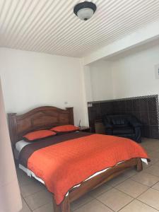 a bedroom with a bed with a red comforter at Hotel y restaurante Tabaconess in Guácimo