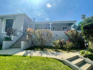 a white house with stairs and flowers in a yard at The Dream Cottage in Los Angeles