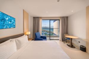 a hotel room with a bed and a view of the ocean at The Arena Apartment Cam Ranh - Free Pool in Cam Ranh