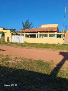 ein Haus auf einer unbefestigten Straße neben einem Zaun in der Unterkunft TRANQUILIDADE- CHAPÉU DO SOL in São João da Barra