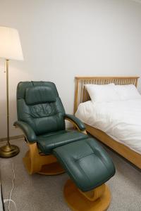 a green chair sitting in a room next to a bed at Ogeum stay in Seoul