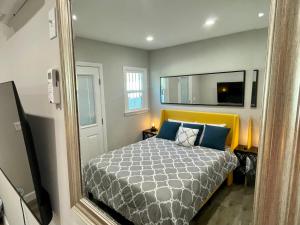 a bedroom with a bed with a yellow headboard and a mirror at The Dream Cottage in Los Angeles