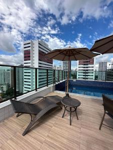 patio con due sedie e ombrellone sul tetto di Excelente localização na zona norte - Sem Taxas a Recife