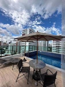 a patio with a table and chairs and an umbrella at Excelente localização na zona norte - Sem Taxas in Recife