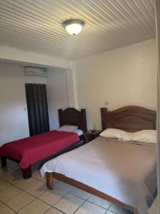 a bedroom with two beds and a red blanket at Hotel y restaurante Tabaconess in Guácimo