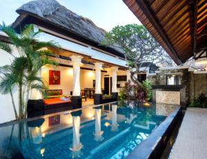 a villa with a swimming pool in front of a house at Villa Cantik Tresna in Seminyak