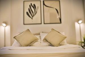 uma cama com duas almofadas e duas fotografias na parede em Luminoso Studio en Santiago Centro HOM em Santiago
