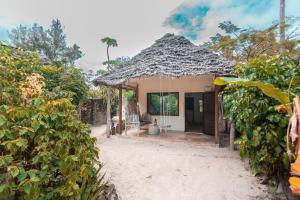 a small house with a thatched roof at B4 Beach Club and Hotel in Paje