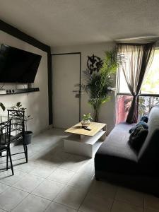 ein Wohnzimmer mit einem Sofa und einem Tisch in der Unterkunft Habitación Cuitláhuac en Apartamento Compartido in Mexiko-Stadt