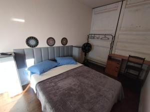 a bedroom with a bed with blue pillows and a desk at Recanto das Pedras Hospedagem in São Thomé das Letras