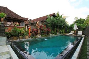 a swimming pool in front of a house at Bale Bali Inn in Ubud