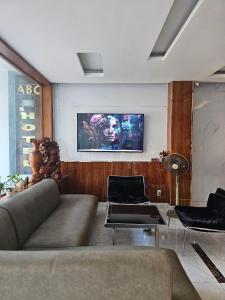 a living room with a couch and a tv on the wall at ABC HOTEL BÌNH TÂN in Ho Chi Minh City