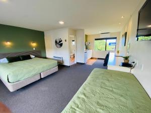 um quarto com 2 camas e uma parede verde em Commodore Motel em Dunedin