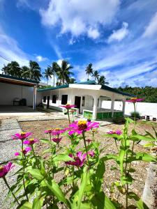 un edificio con flores rosas delante de él en NOGS Homestay, near Magpupungko, Siargao Island Surfings Spots en Pilar