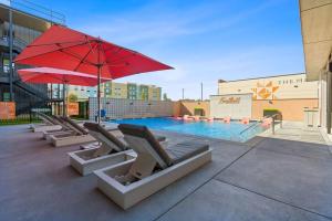 einen Pool mit Liegestühlen und einem roten Sonnenschirm in der Unterkunft Luxury Condo in Prime Location (Pet-Friendly) in New Braunfels