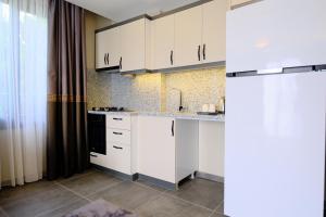 uma cozinha com armários brancos e um fogão preto em LİMONOTTO SUİT OTEL em Çiftlikköy