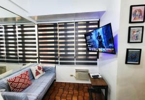 ein Wohnzimmer mit einem Sofa und einem Flachbild-TV in der Unterkunft Bright Makati Glass View By GreenBelt in Manila