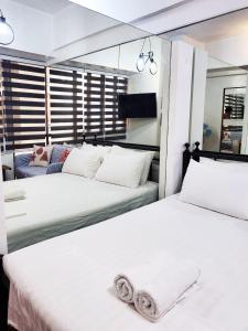 2 Betten in einem Schlafzimmer mit weißer Bettwäsche in der Unterkunft Bright Makati Glass View By GreenBelt in Manila