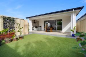 a backyard with a green lawn in front of a house at Modern 3 BR home in Fulham in Henley Beach South