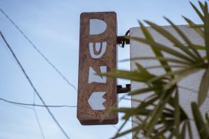 una señal con la palabra deuda colgando de un edificio en Dune Seseh en Munggu