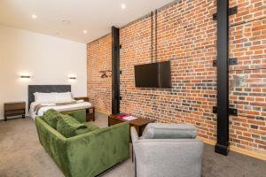 Cette chambre est dotée d'un mur en briques, d'un lit et d'une télévision. dans l'établissement Princes St Apartments, à Dunedin